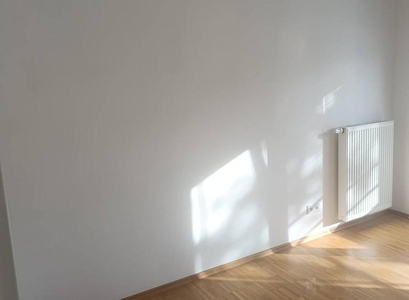 Leeres, sonniges Zimmer mit Parkettboden nach der Räumung